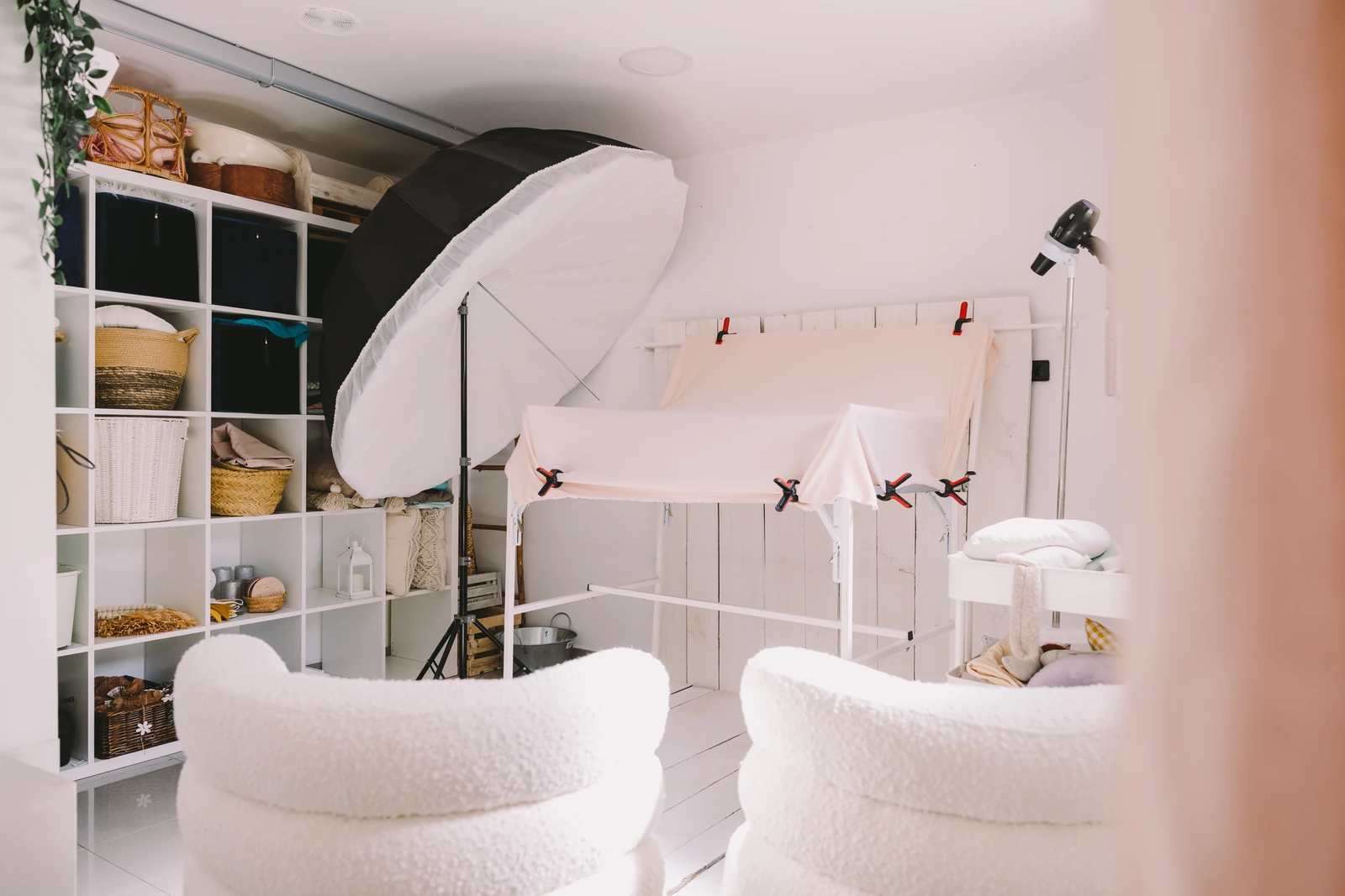 El estudio de Mave Studio en O Burgo: mesa de posado newborn, estanterías con el atrezzo y dos butacas blancas
